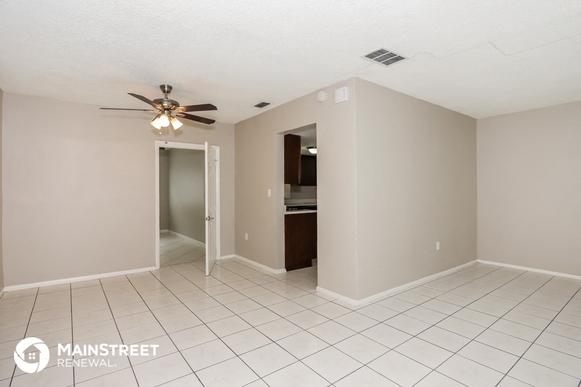 a spacious living room with tile flooring and a ceiling fan