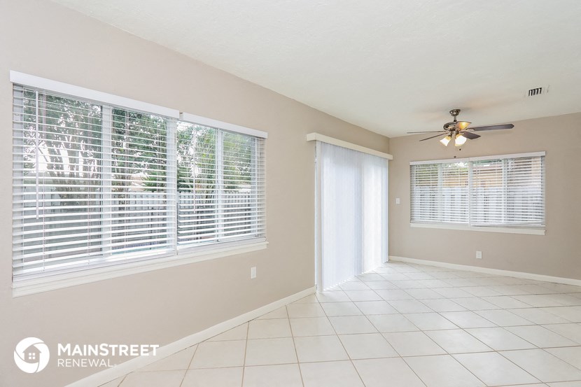 a living room with a large window and a ceiling fan