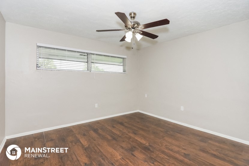 the spacious living room of this manufactured home has wood flooring and a ceiling fan