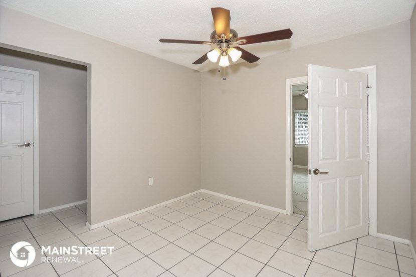 a empty room with a ceiling fan and a door to a bathroom