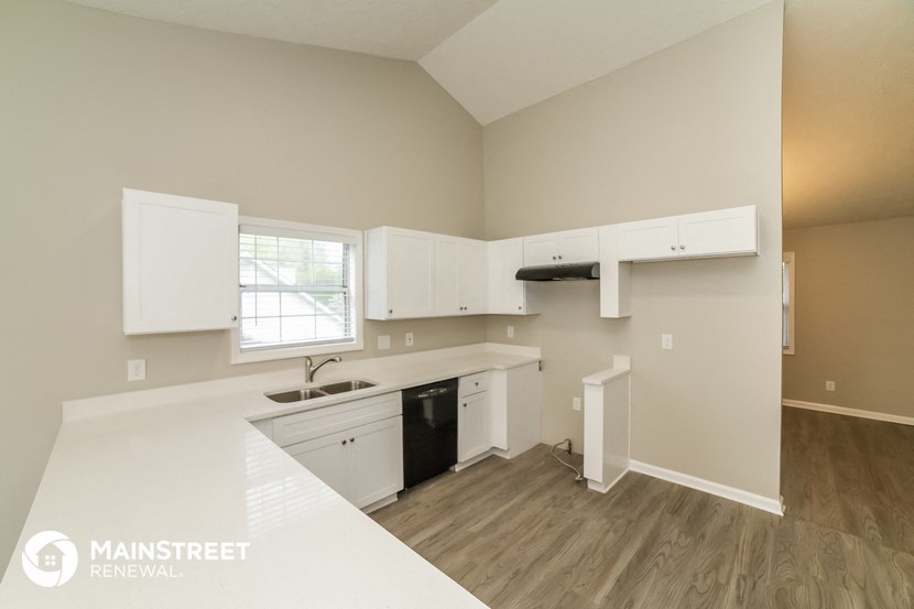 a kitchen with white cabinets and a sink and a window