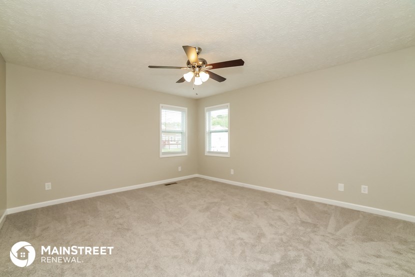 the spacious living room with carpeting and a ceiling fan