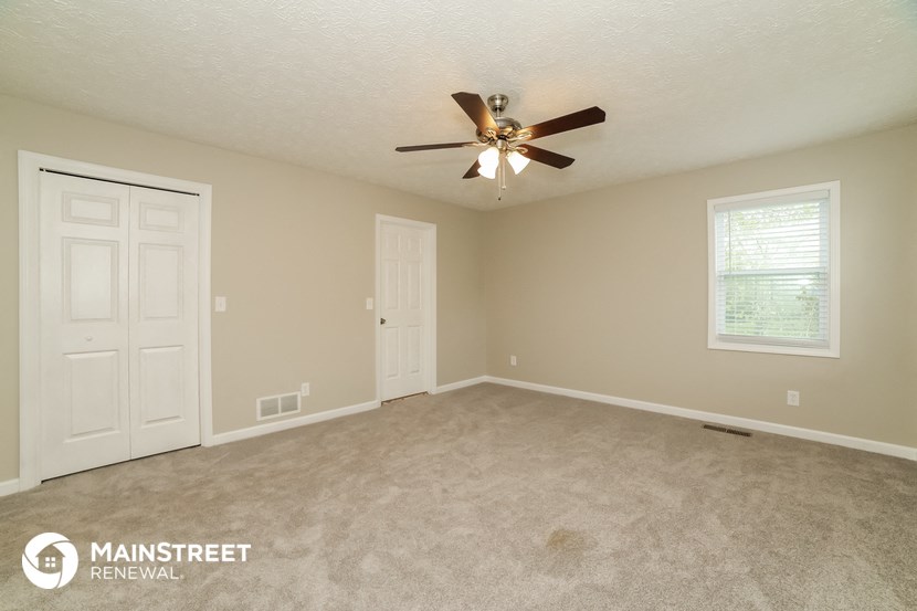 the master bedroom has a carpeted floor and a ceiling fan