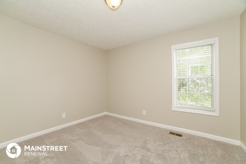 the upstairs bedroom with carpeted flooring and a window