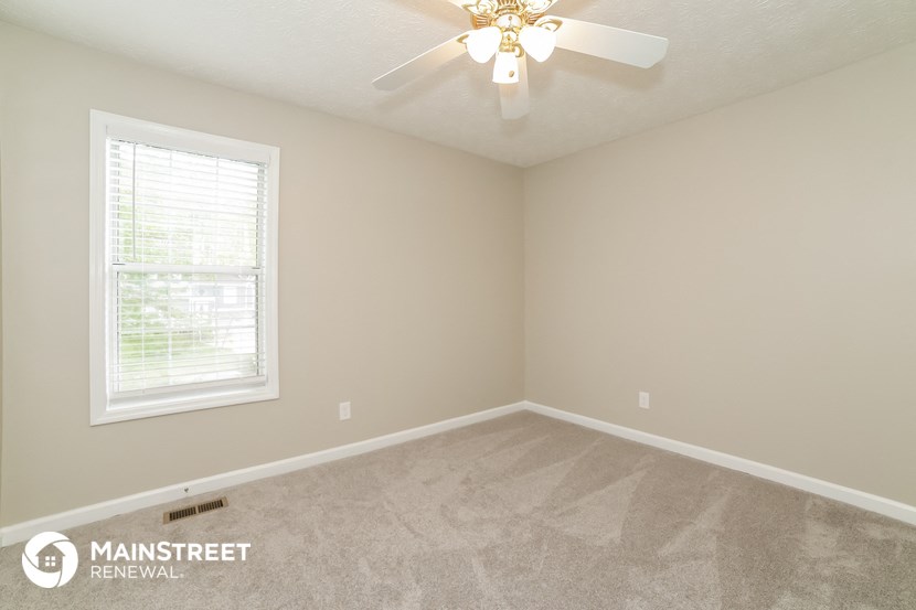 the upstairs bedroom has a ceiling fan and a window