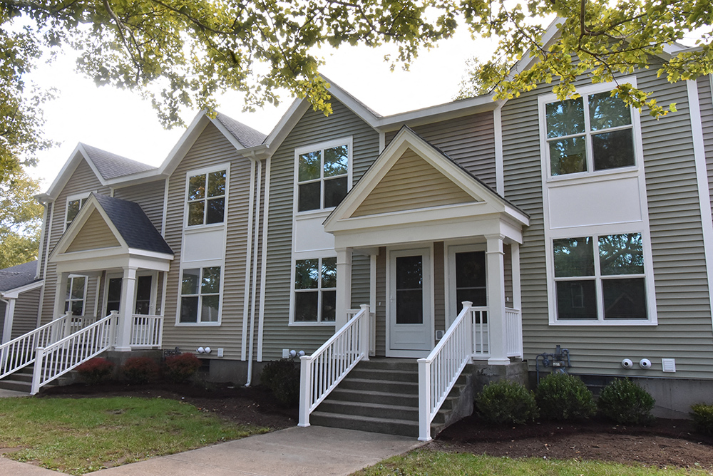a gray house with white railings and a sidewalk