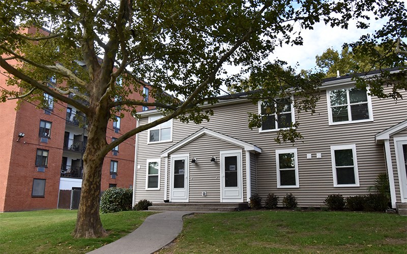 a house with a sidewalk in front of it next to a tree
