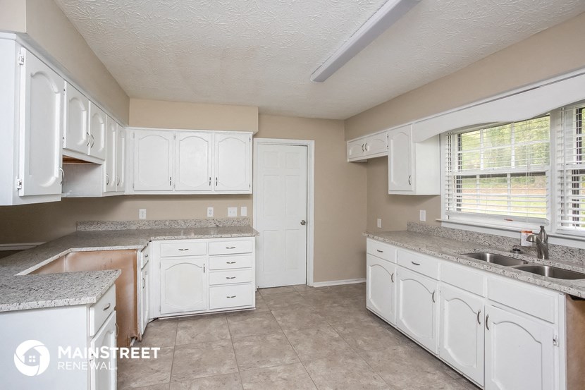 a kitchen with white cabinets and a sink and a window