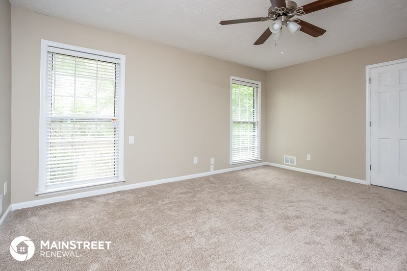 the master bedroom with carpet and a ceiling fan