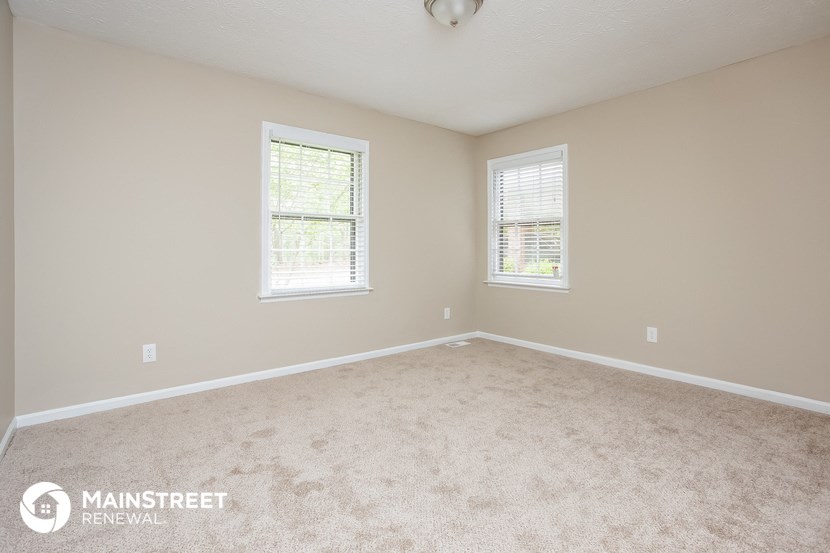 a bedroom with a carpeted floor and two windows