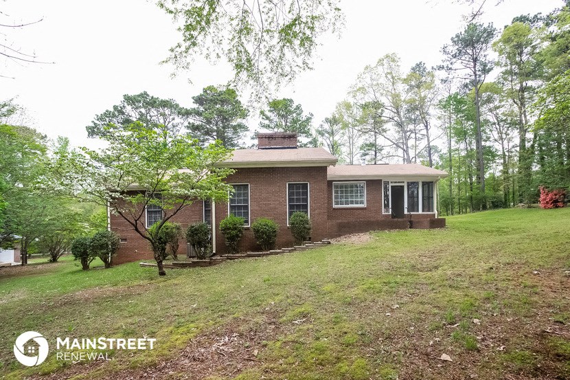 a small brick house on a hill with trees