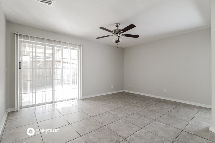 the living room of an empty home with a ceiling fan