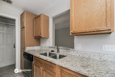 a kitchen with marble countertops and wooden cabinets and a sink