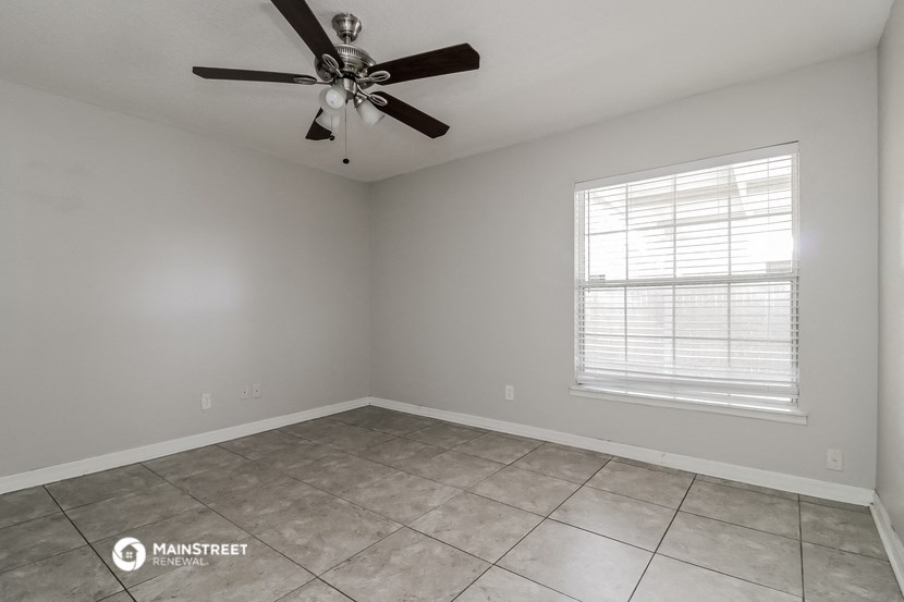 the spacious living room with ceiling fan and tiled floor