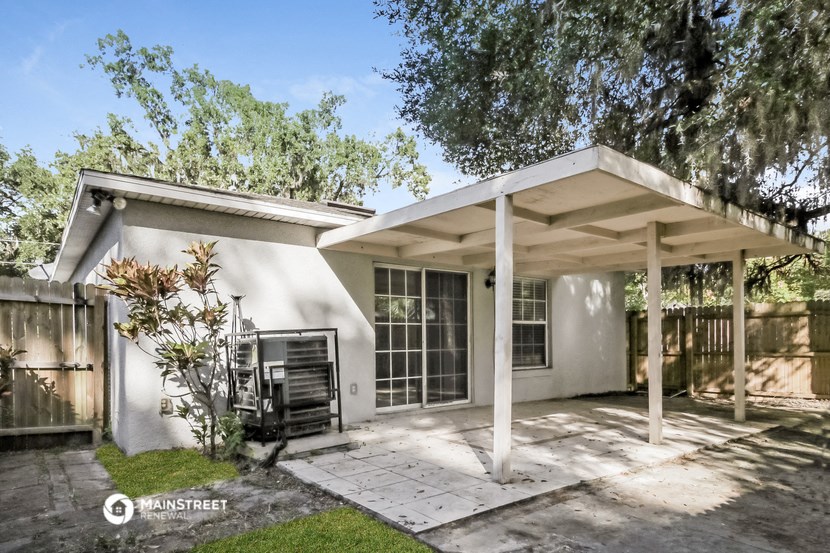 the exterior of a small white house with a patio