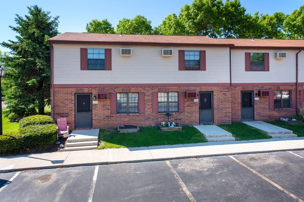 a brick and white building with a lawn in front