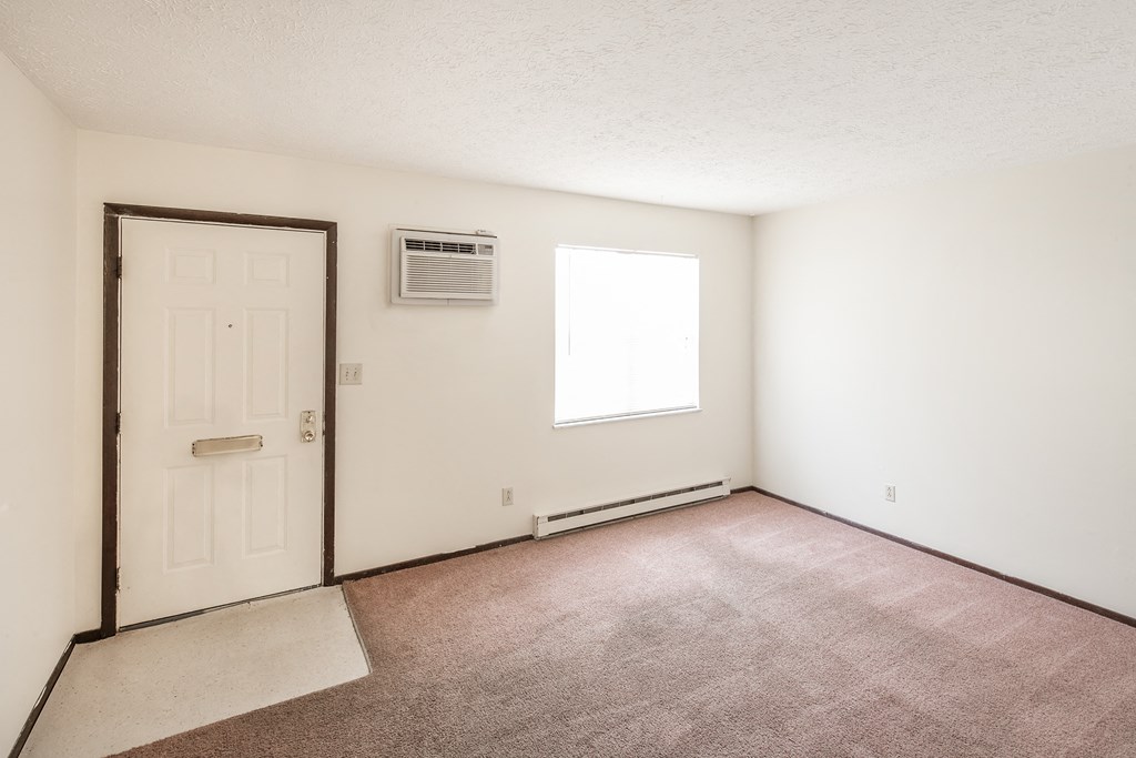 an empty living room with a white door and a window
