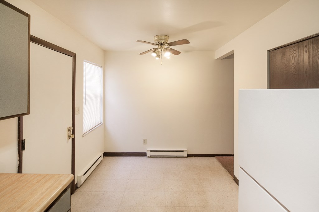 an empty kitchen with a refrigerator and a ceiling fan