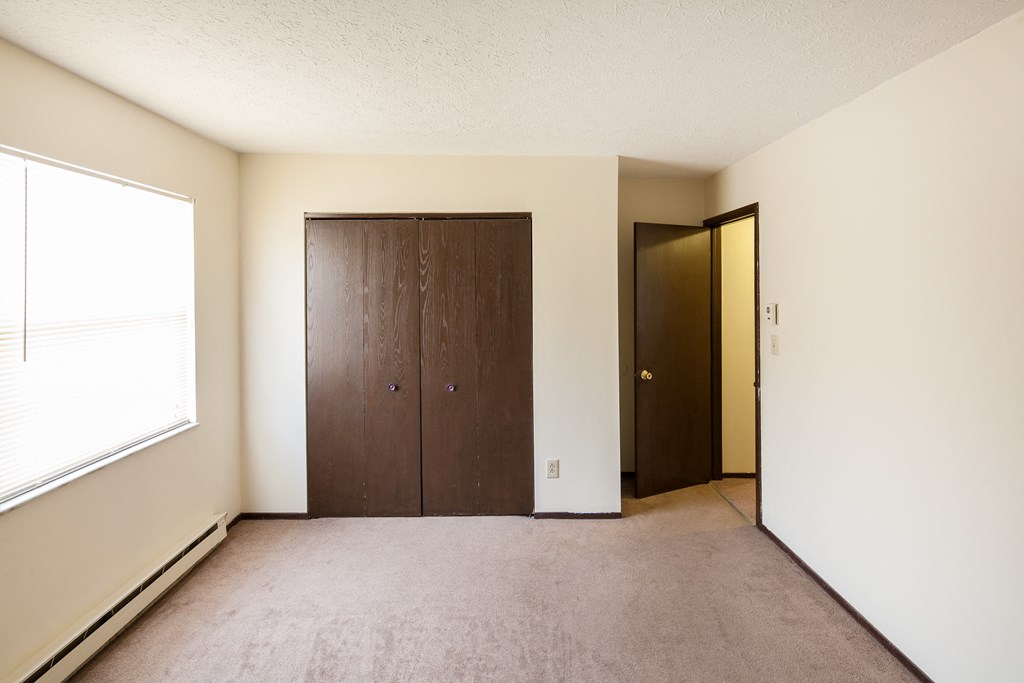 an empty room with a closet and a window