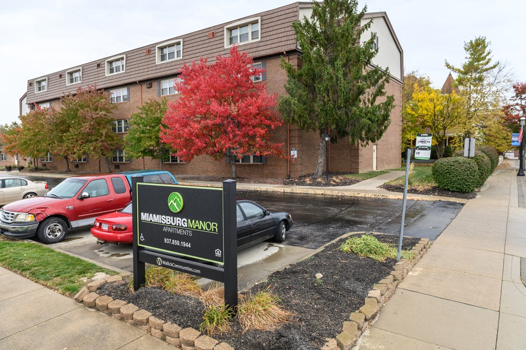 an apartment building with a sign in front of a parking lot