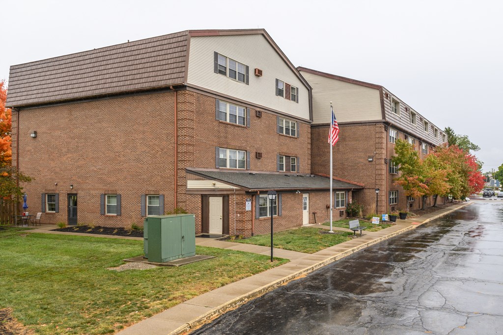 a brick building with an flag in front of a wet street