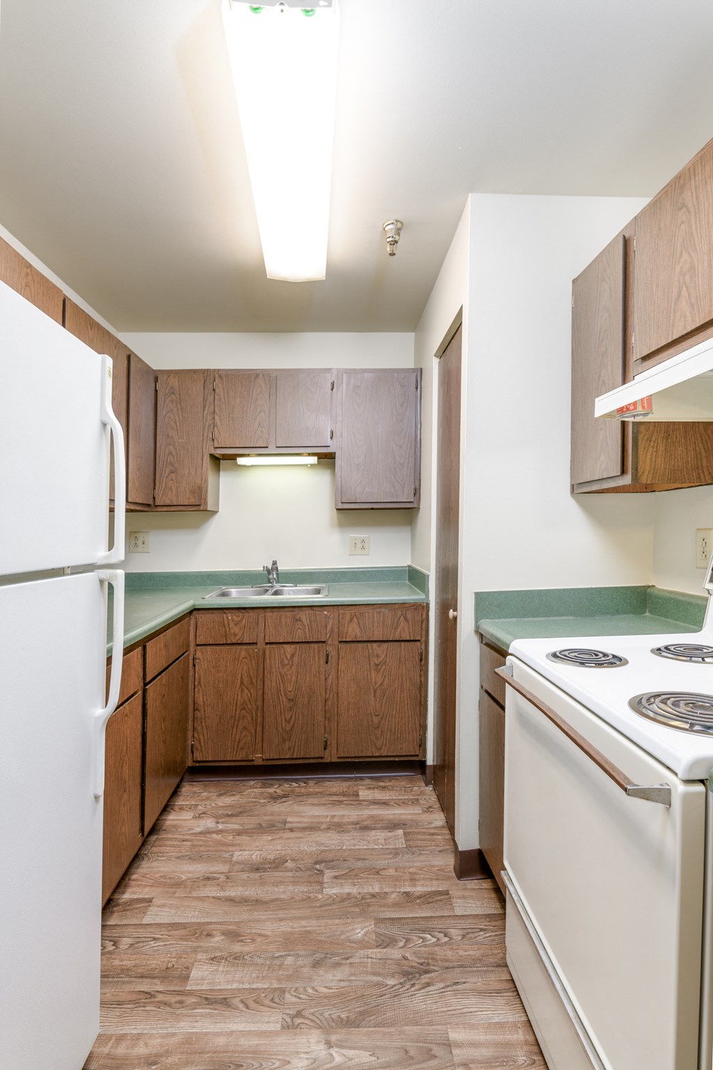 an empty kitchen with white appliances and wooden cabinets