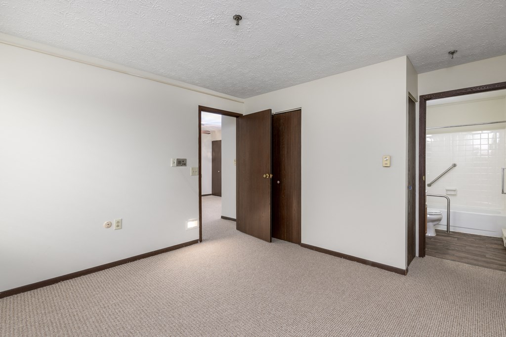 an empty room with a door to a bathroom and a closet