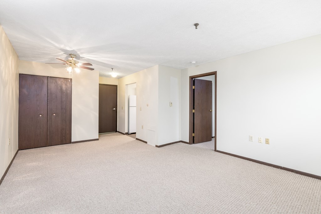 the living room of an empty apartment with a ceiling fan