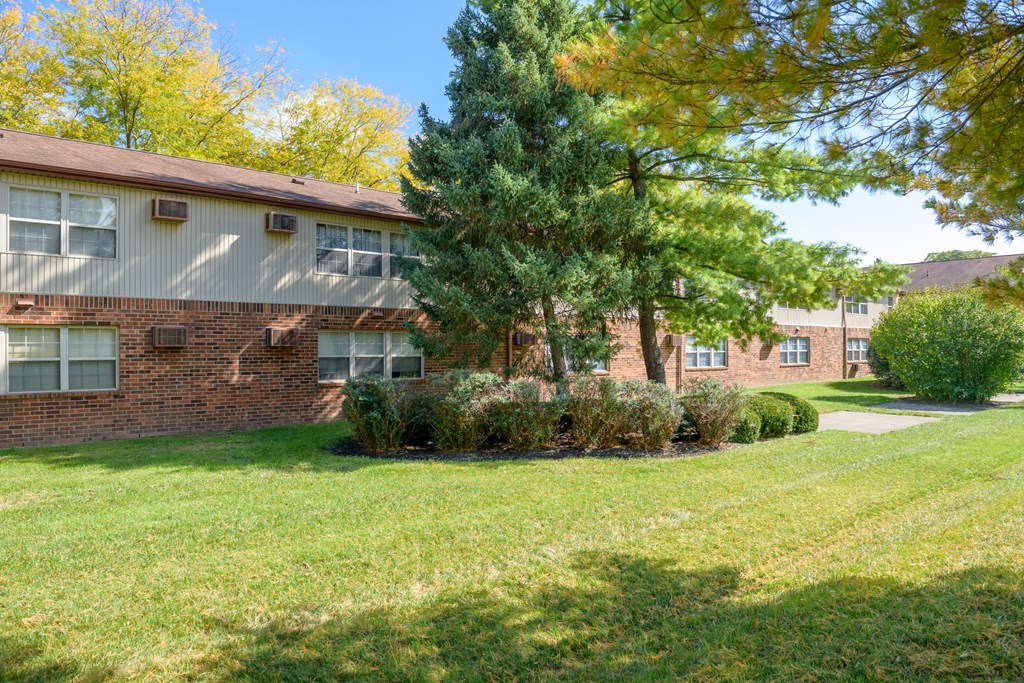 exterior view of a brick apartment building with grass and trees