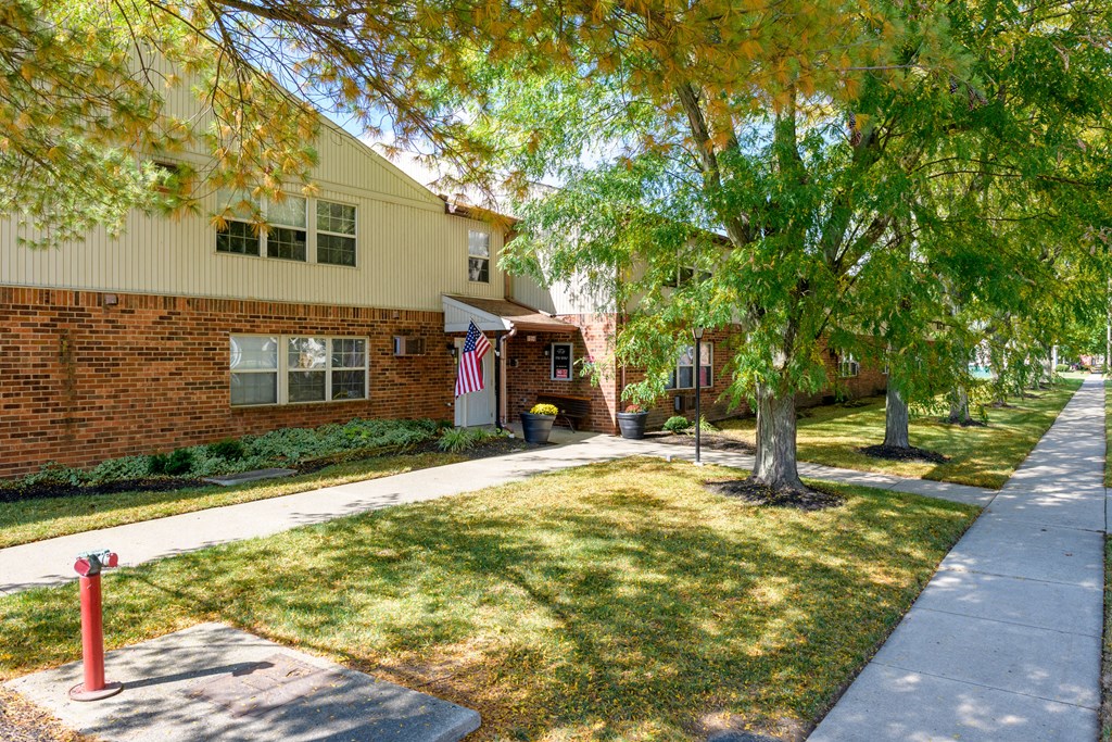 the front of a brick house with a lawn and trees