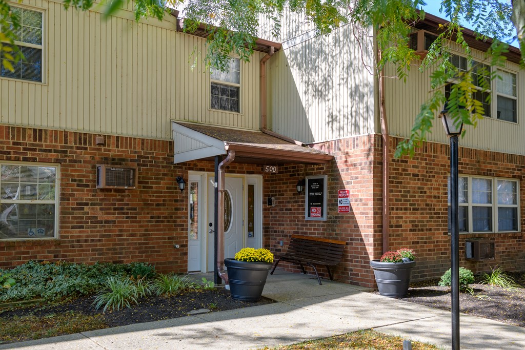 the front of a brick building with a porch and a bench