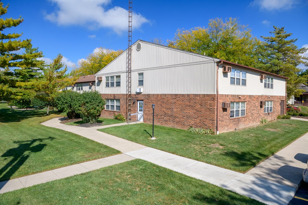 the front of a brick building with a sidewalk and grass