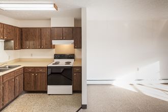 an empty kitchen with white appliances and wooden cabinets