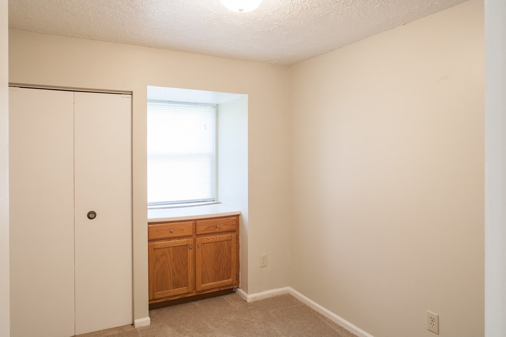 an empty room with a window and a closet
