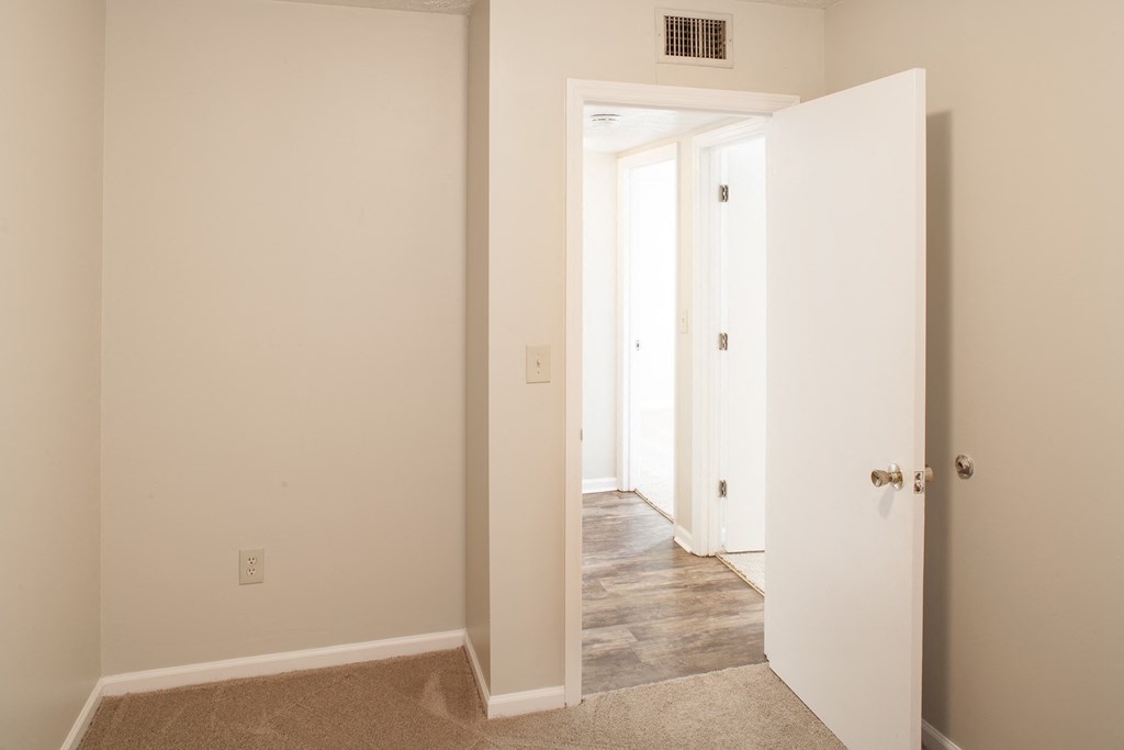 a bedroom with white walls and a door open to a hallway