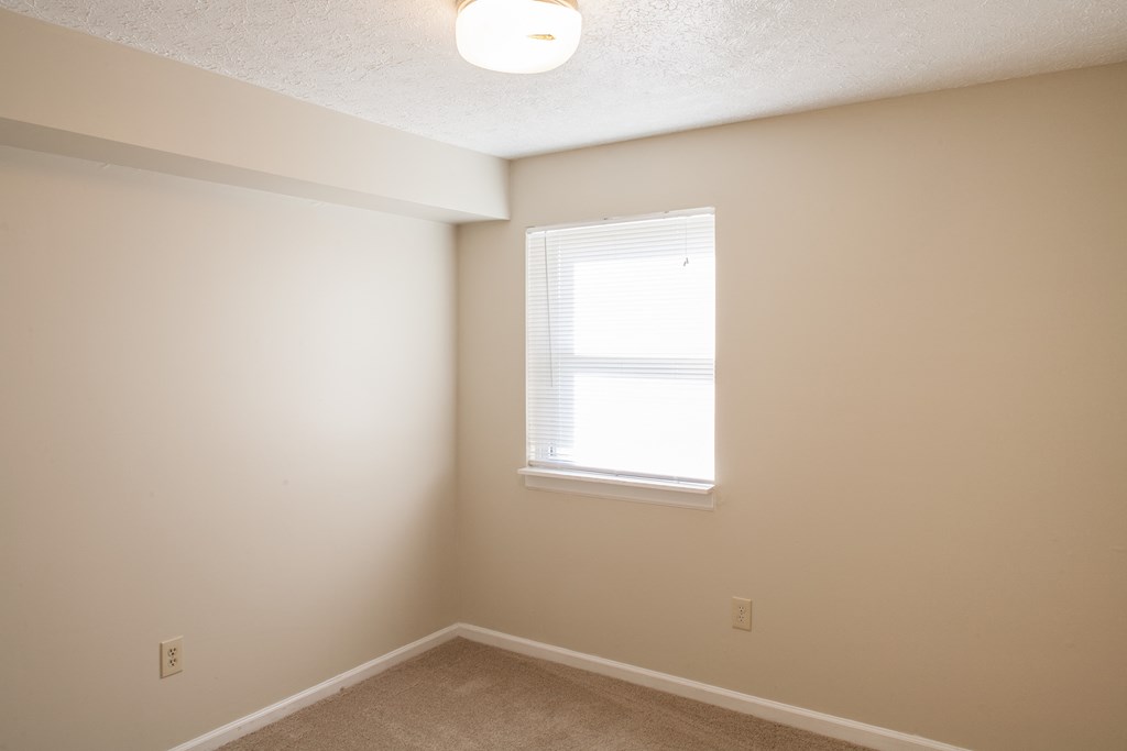 a bedroom with white walls and a window