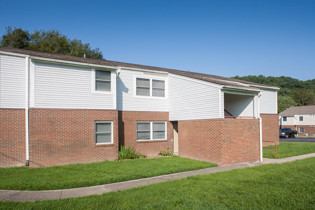 a brick building with white siding and green grass