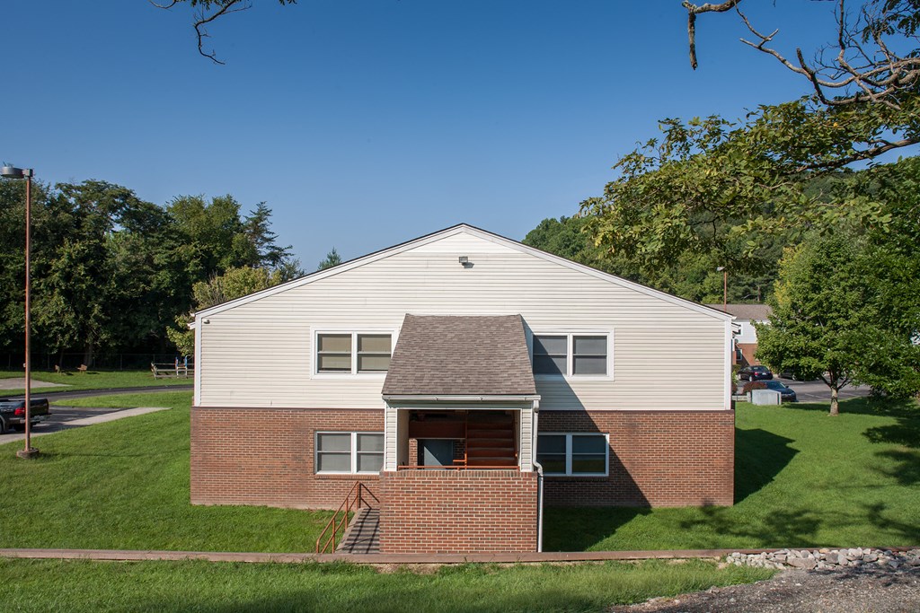 the front of a brick building with a lawn and trees