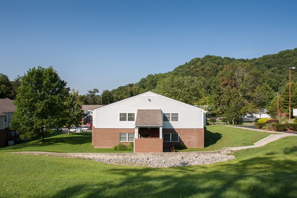 an aerial view of a white and brick building with a hill in the background