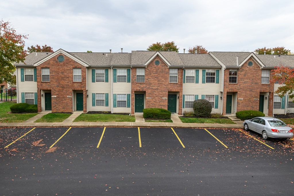 an apartment building with a parking lot and a car parked in front