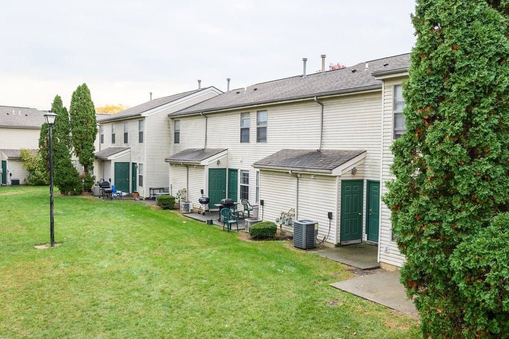 a row of white houses with green doors and a lawn