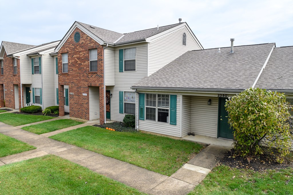 a row of white houses with green shutters and a sidewalk