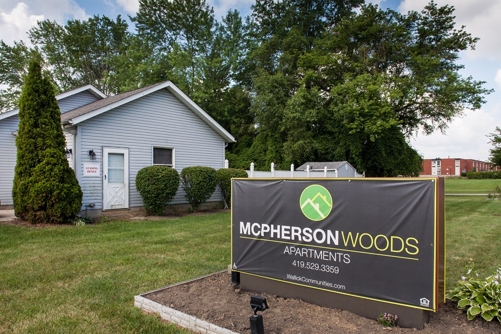 a mcpherson woods apartments sign in front of a house