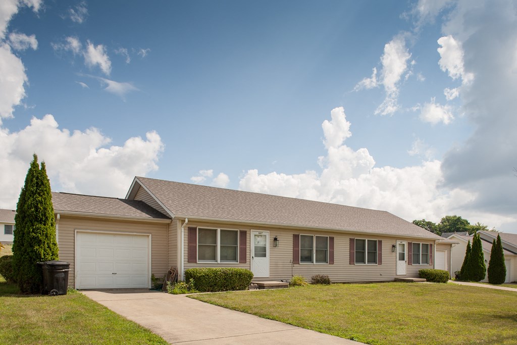 a beige house with a driveway and a lawn