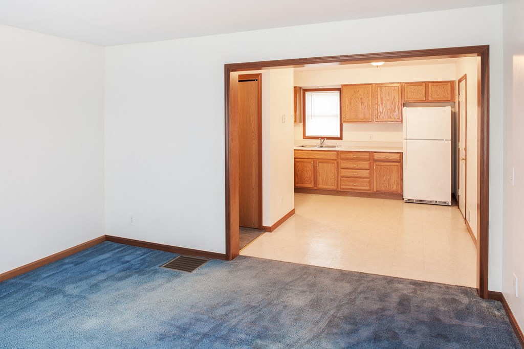 an empty living room and kitchen with a blue rug