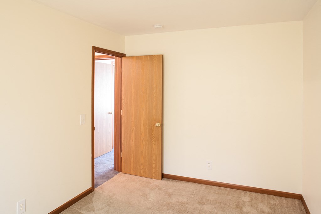 a bedroom with a door to a hallway and a carpeted floor