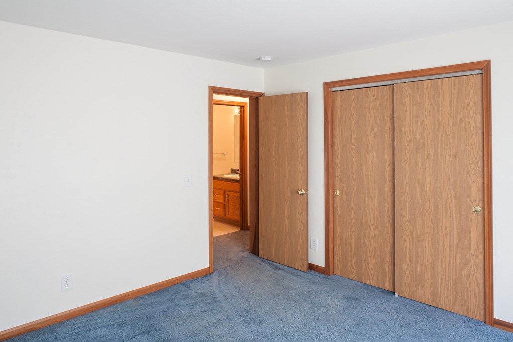 a bedroom with two doors and a doorway to a bathroom