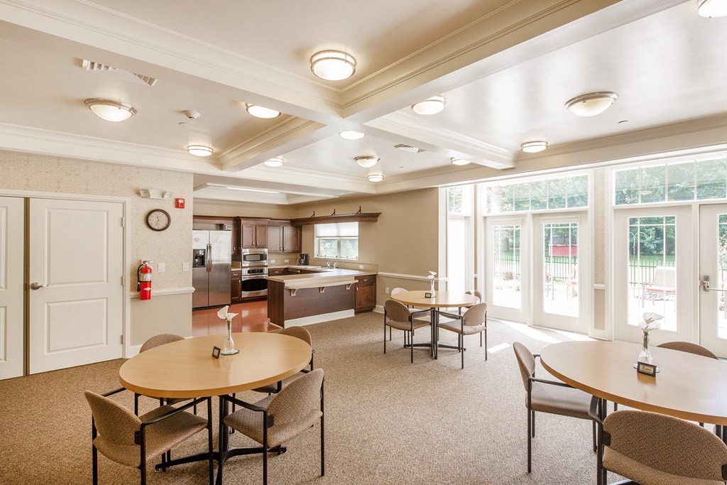 a community room with tables and chairs and a kitchen