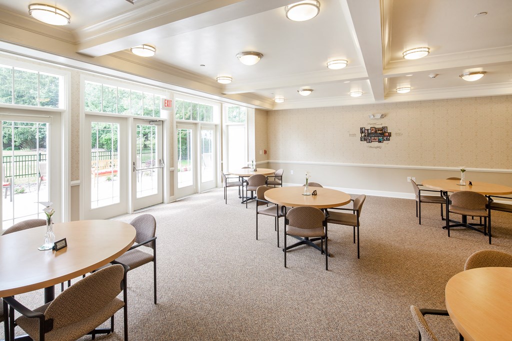 a multipurpose room with tables and chairs and large windows