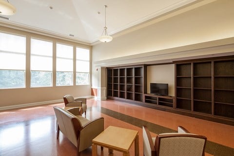 a living room with chairs and tables and a bookshelf